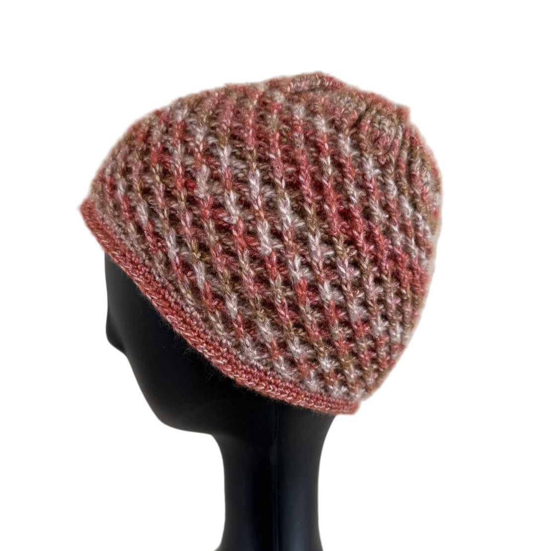 A handmade crochet spirograph beanie in red, brown, and beige shades displayed on a mannequin head.