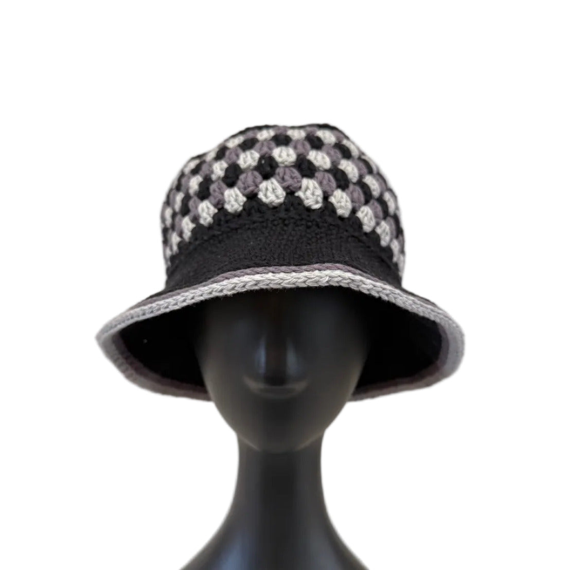 A black/grey crocheted bucket hat displayed on a black mannequin head on a white background