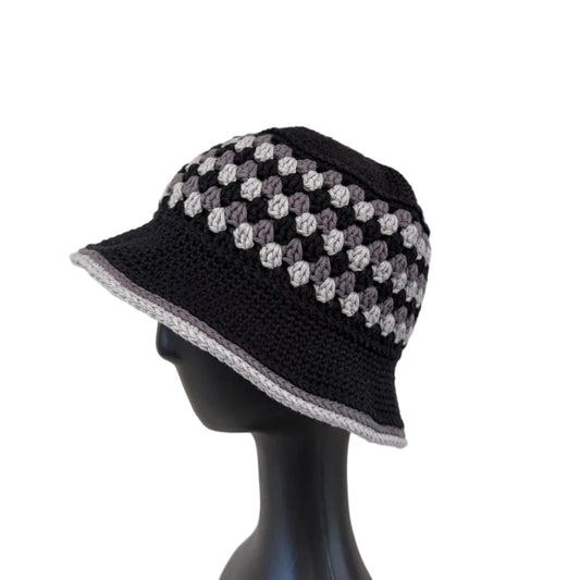 A black/grey crocheted bucket hat displayed on a black mannequin head on a white background