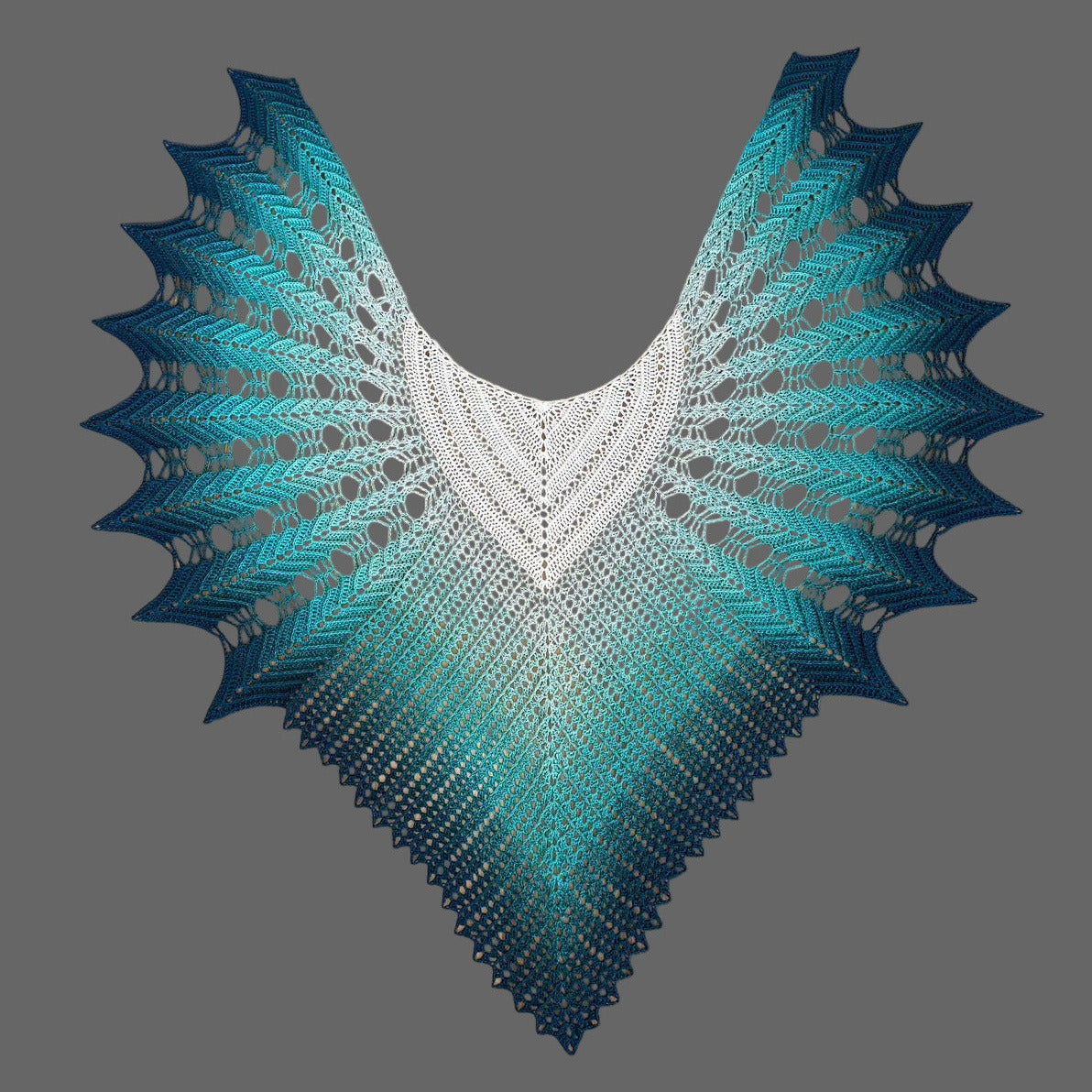 Veilwyn shawl - lace shawl with a color gradient, featuring a white that fades into teal and dark teal toward the pointed lower edges, displayed against a solid gray background.