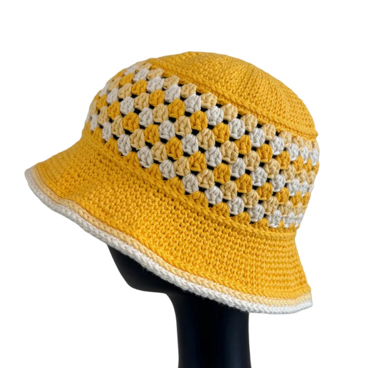 A yellow crocheted bucket hat displayed on a black mannequin head on a white background